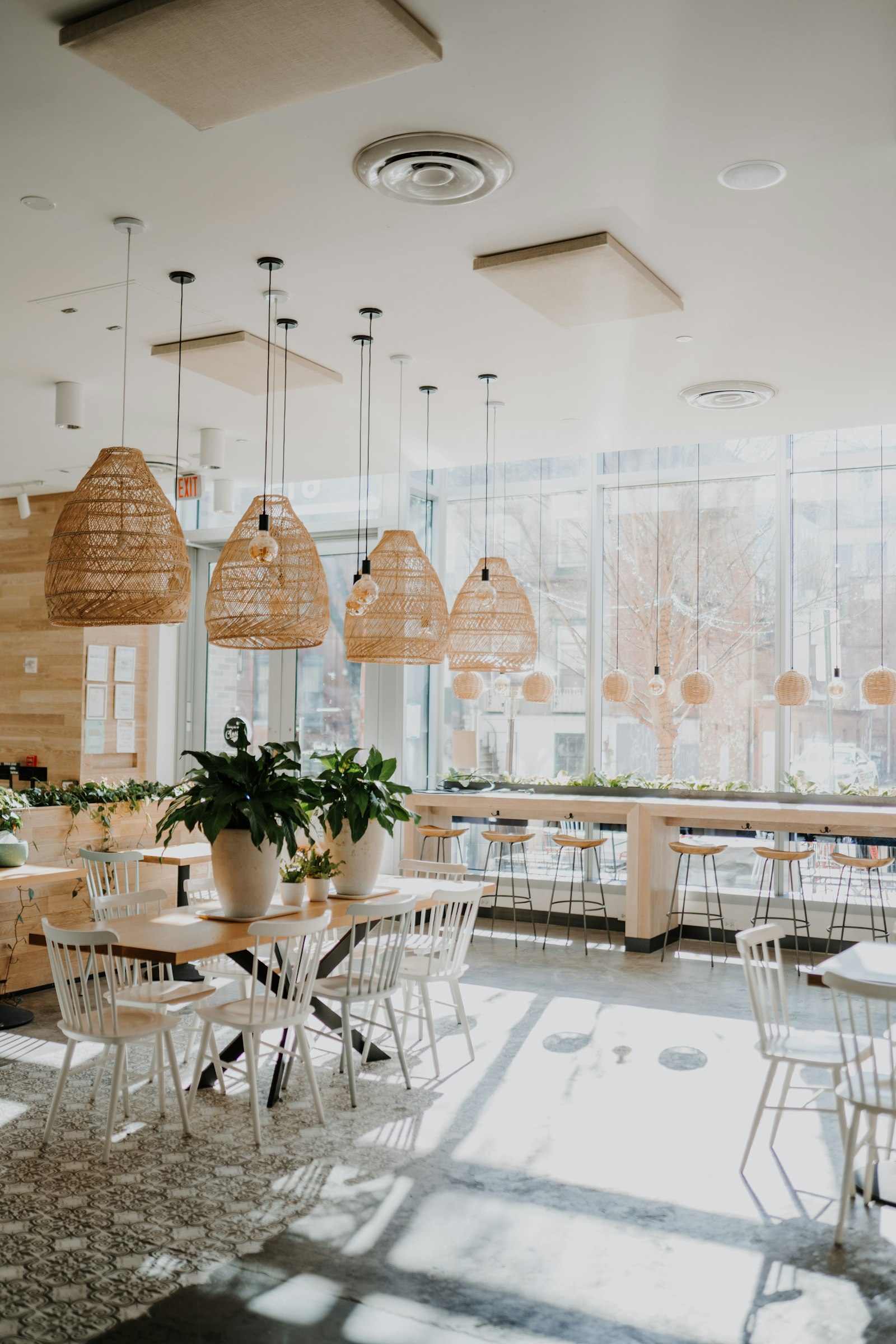 Salón luminoso con mesas de madera y lámparas de mimbre